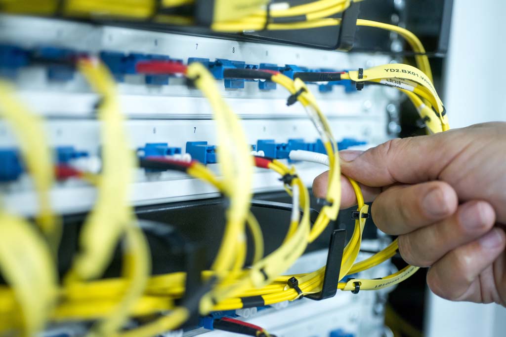 human hand fixing fiber glass cable into control panel